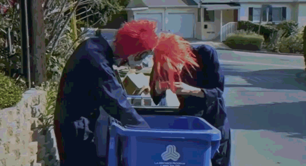 Two clowns rummaging through a bin eating garbage
